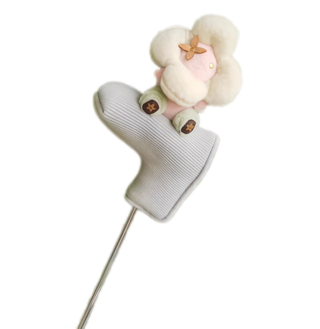 Cream flower plush sitting atop a grey ribbed knit golf putter headcover, brown monogram petal detail in centre