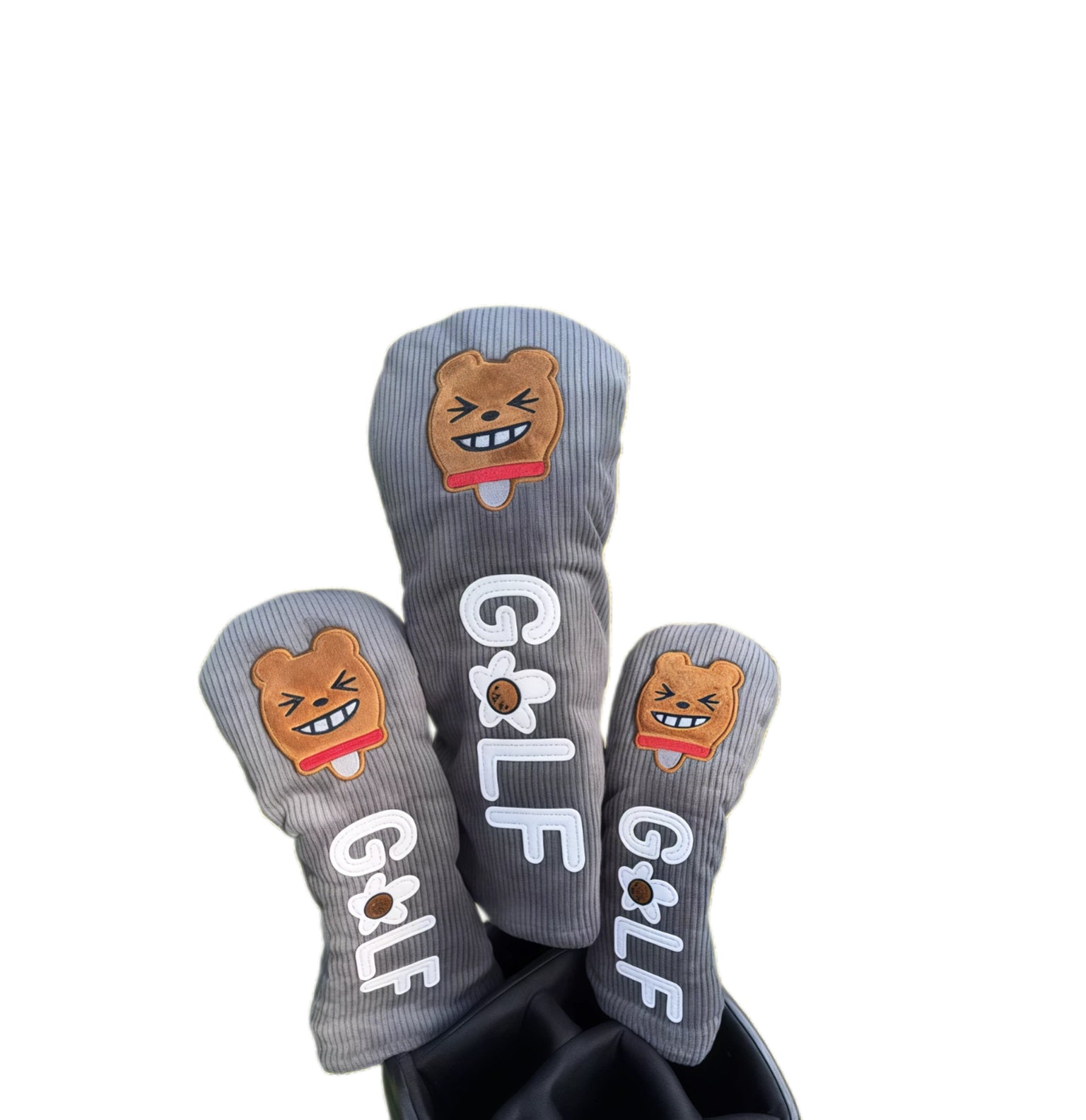 Grey corduroy golf headcovers set with embroidered smiling bear face and “GOLF” letters, designed for driver, fairway and utility clubs with durable protection.