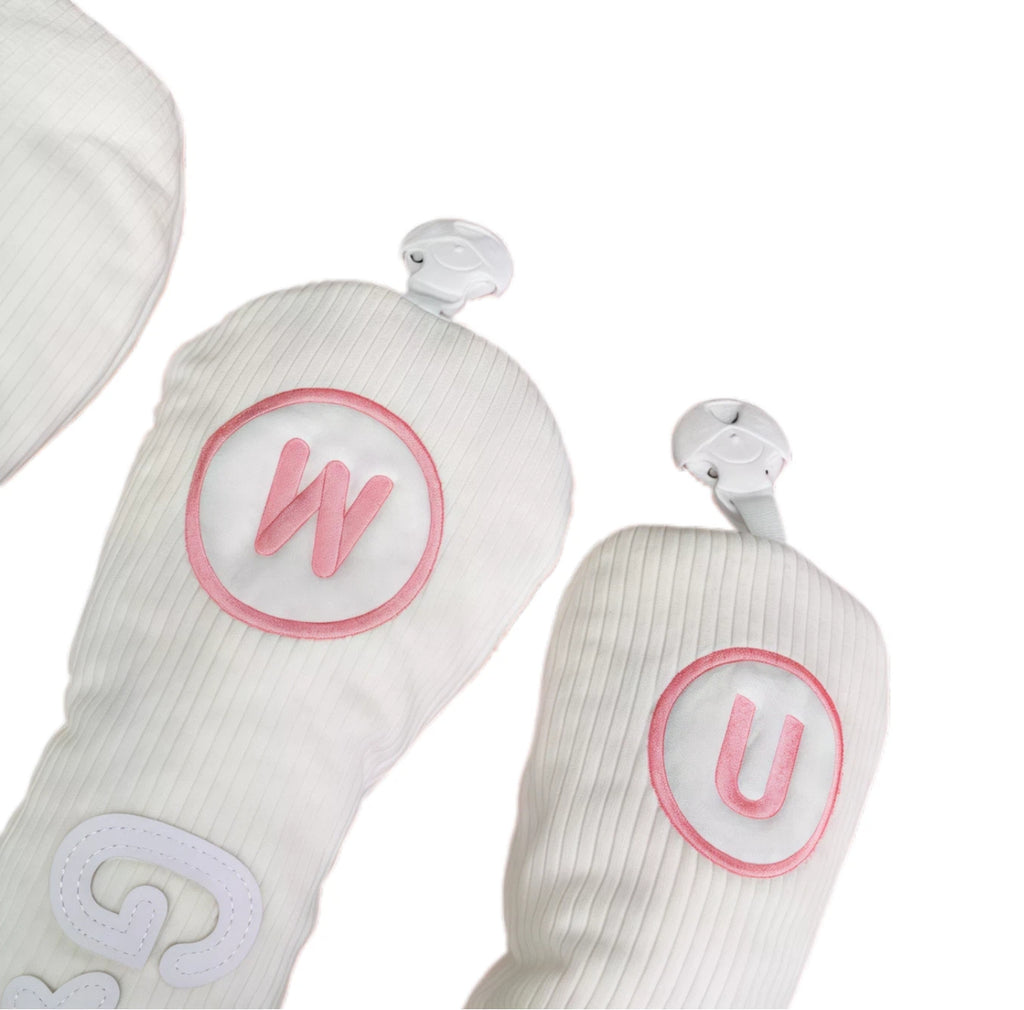 Close-up of corduroy golf headcovers for fairway and utility clubs featuring snap closure and pink lettering (W, U), made of soft corduroy material for scratch-resistant protection.