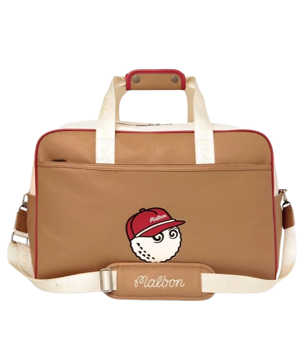 Front view of tan Malbon golf duffle bag featuring red trim, white top handles, and cartoon golf ball wearing a red cap with "Malbon" logo