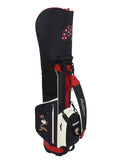 Side view of Malbon Golf stand bag in navy blue, white, and red PU leather featuring a cartoon golf ball character wearing a patriotic hat, brand tag, and "Malbon" script logo.