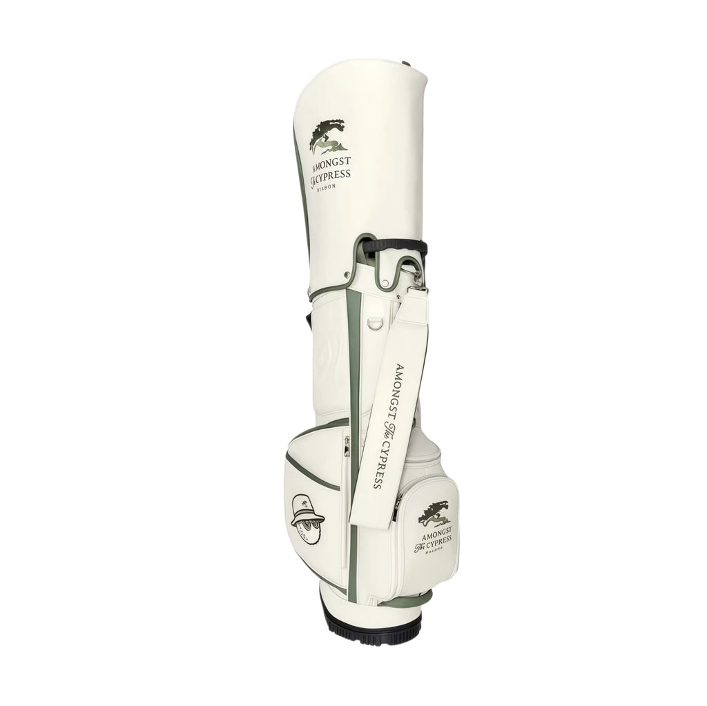 Front view of Malbon Golf Stand Bag featuring white and green PU leather design with "Amongst The Cypress" logo, shoulder strap, and cartoon golf ball mascot patch. Premium waterproof carry bag for men and women.